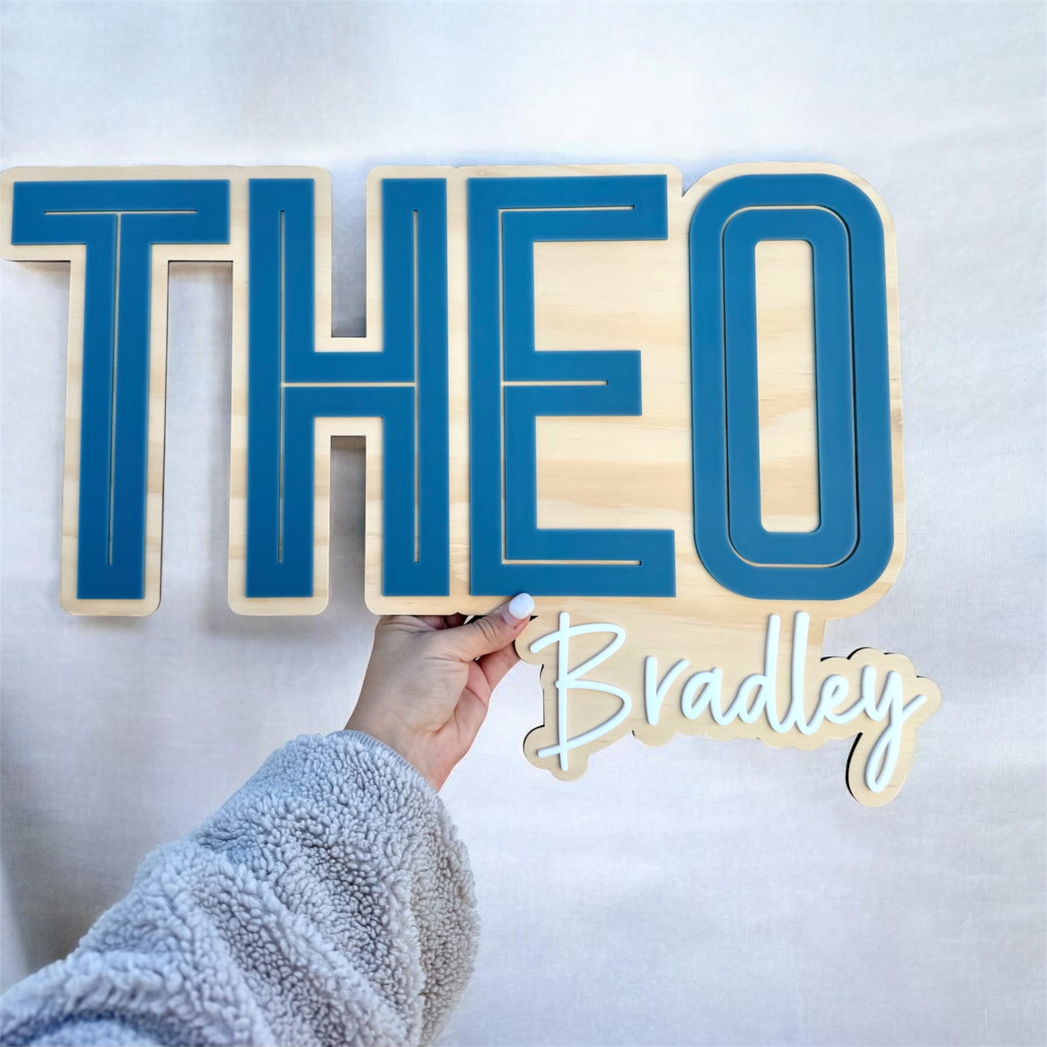 Personalised layered name sign with bold blue Theo lettering and Bradley script on timber backing