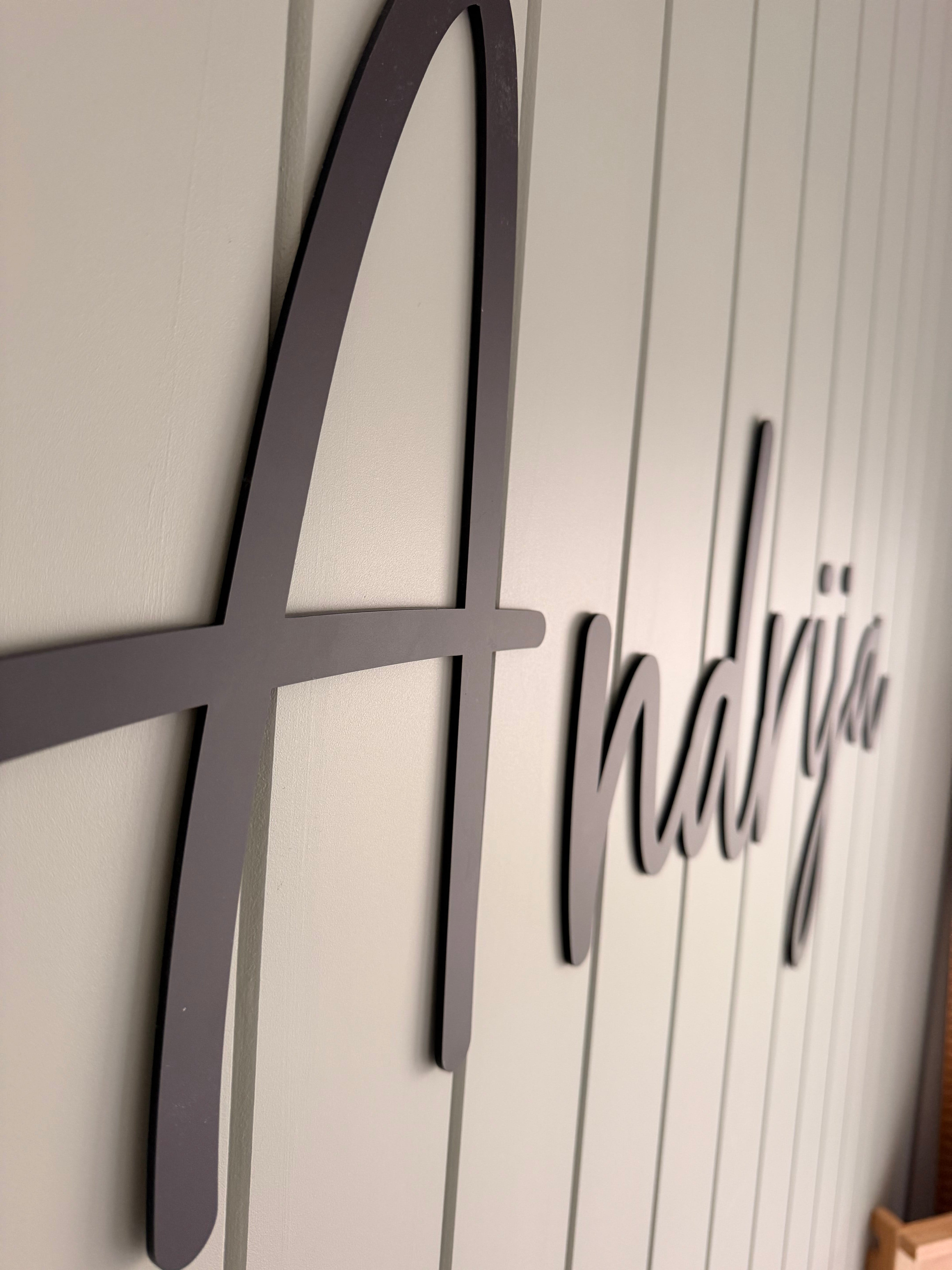 Black Acrylic Name Sign against a white panelled wall with the word Andrija