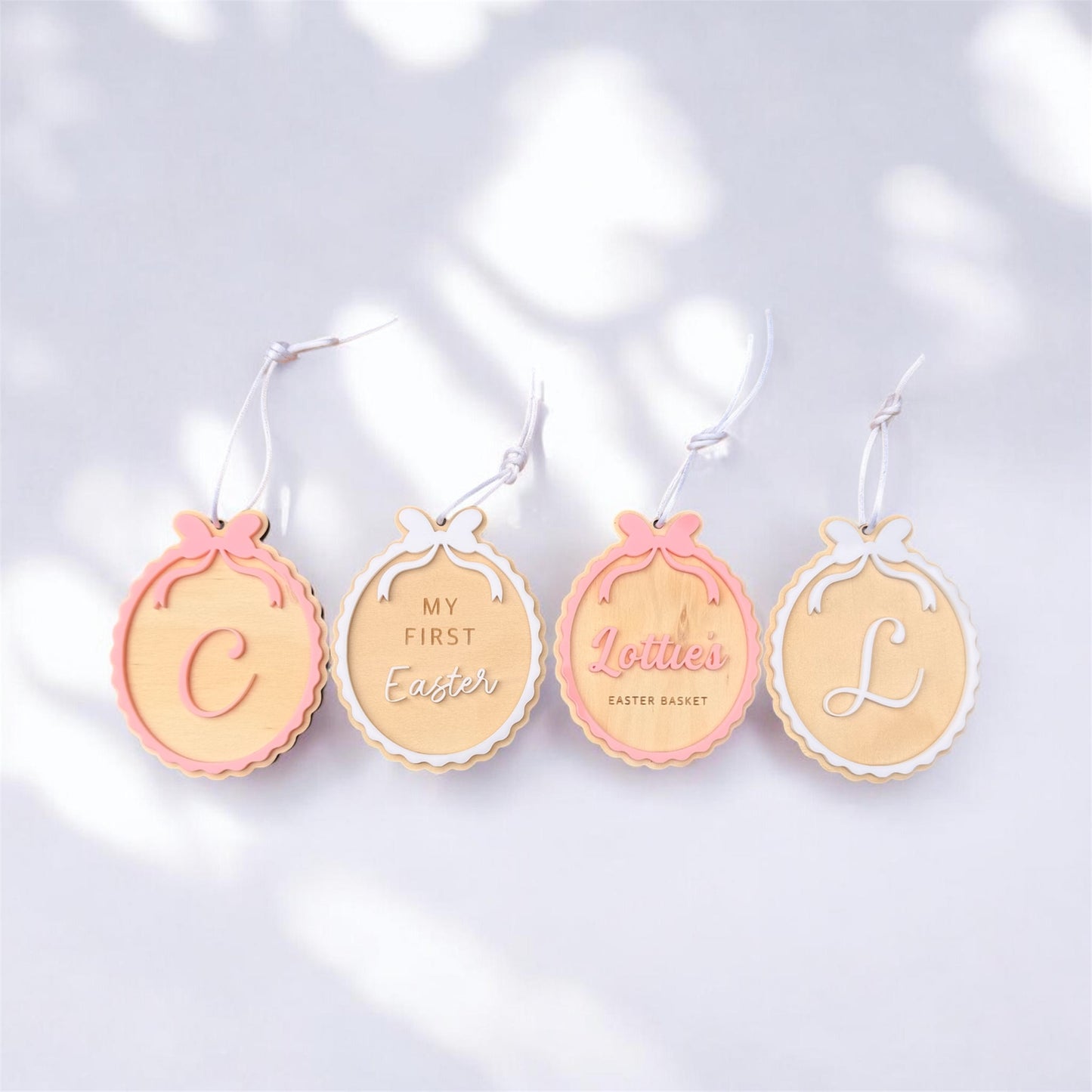 4 Easter Tags flat lay with 4 different designs of C, My first Easter bow design, Personalised name Lottie in pink bow design and letter L in white.