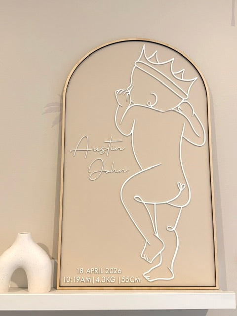 Wall art of a baby with a crown and the birth details including name, date, weight and height. The baby represents the exact height of baby at birth