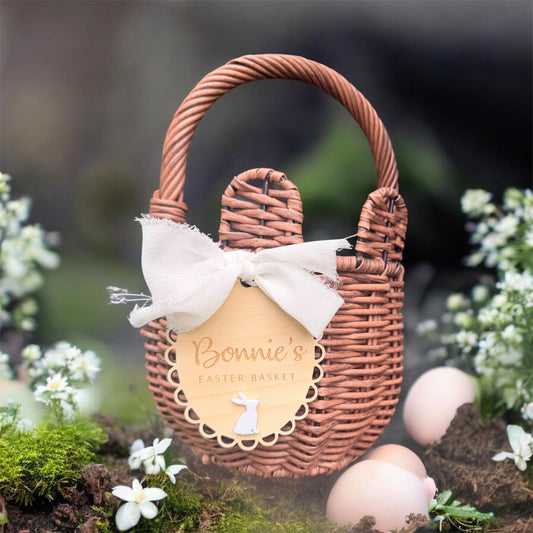 Personalised Easter basket tag with fabric bow in white or blush pink, scalloped wooden bunny name plaque attached to woven basket.