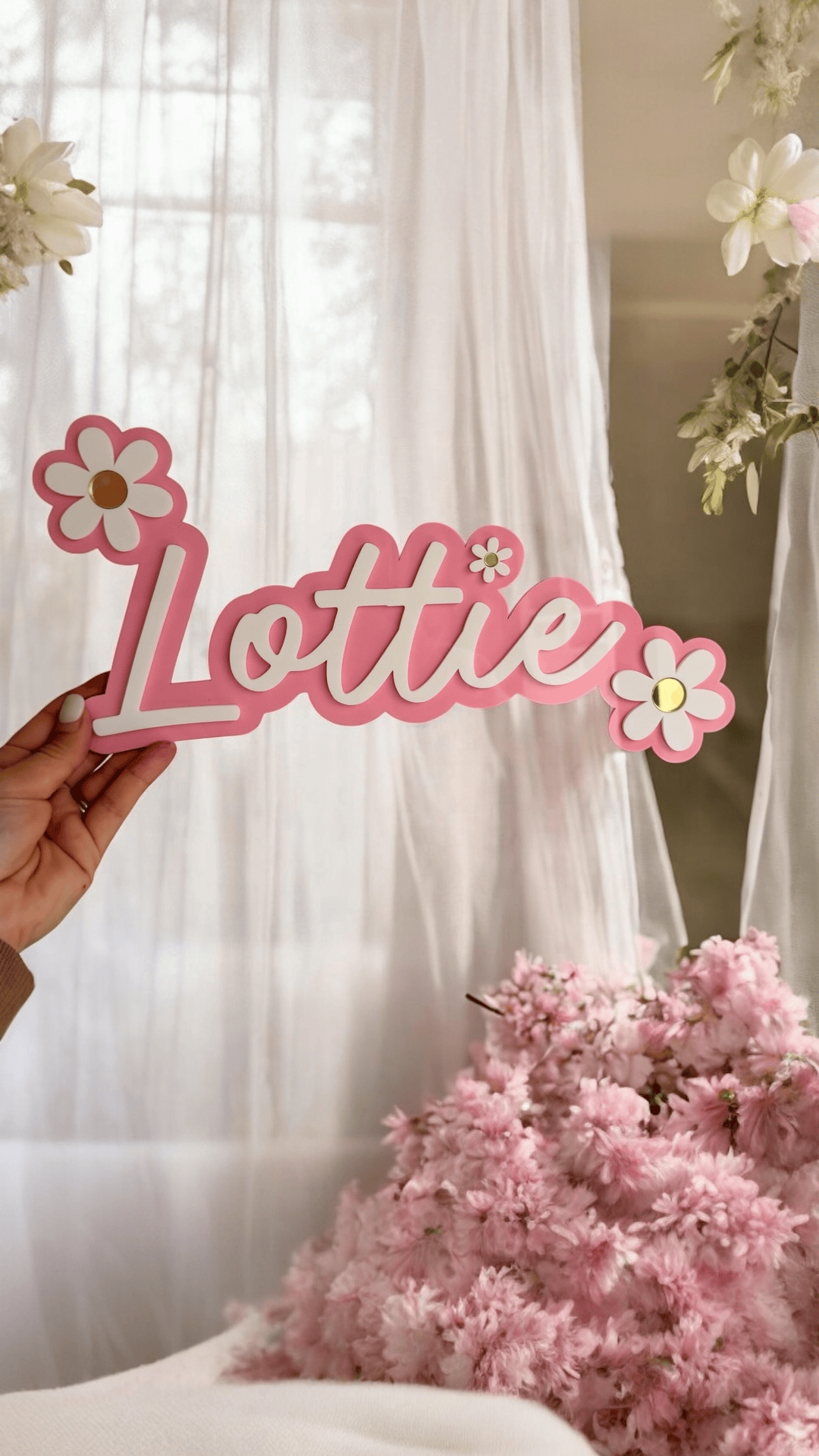 Pink Personalised Daisy name sign with white lettering and floral details for baby girl nursery wall decor.