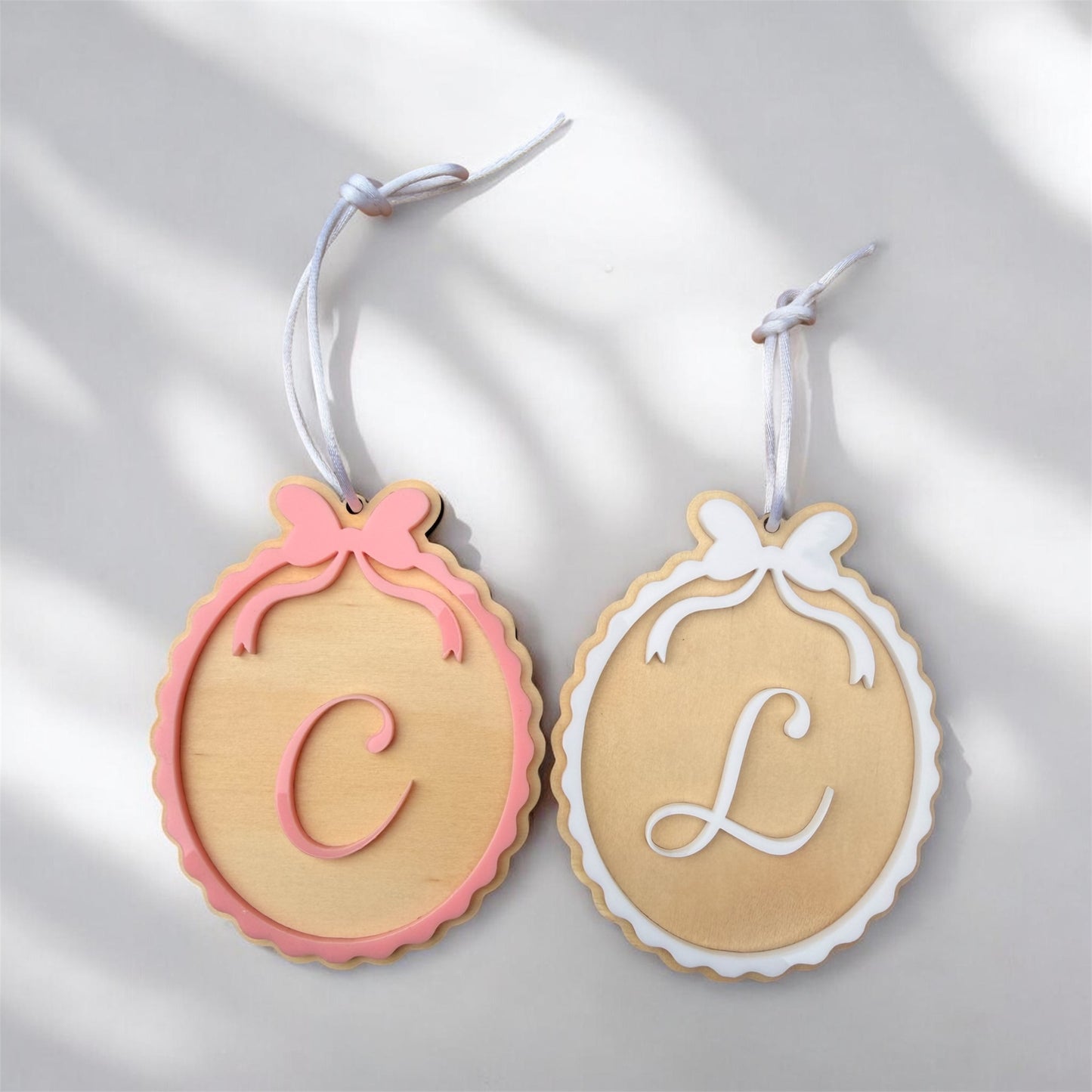 Decorative ornaments with C and L with white and pink bows in scalloped design