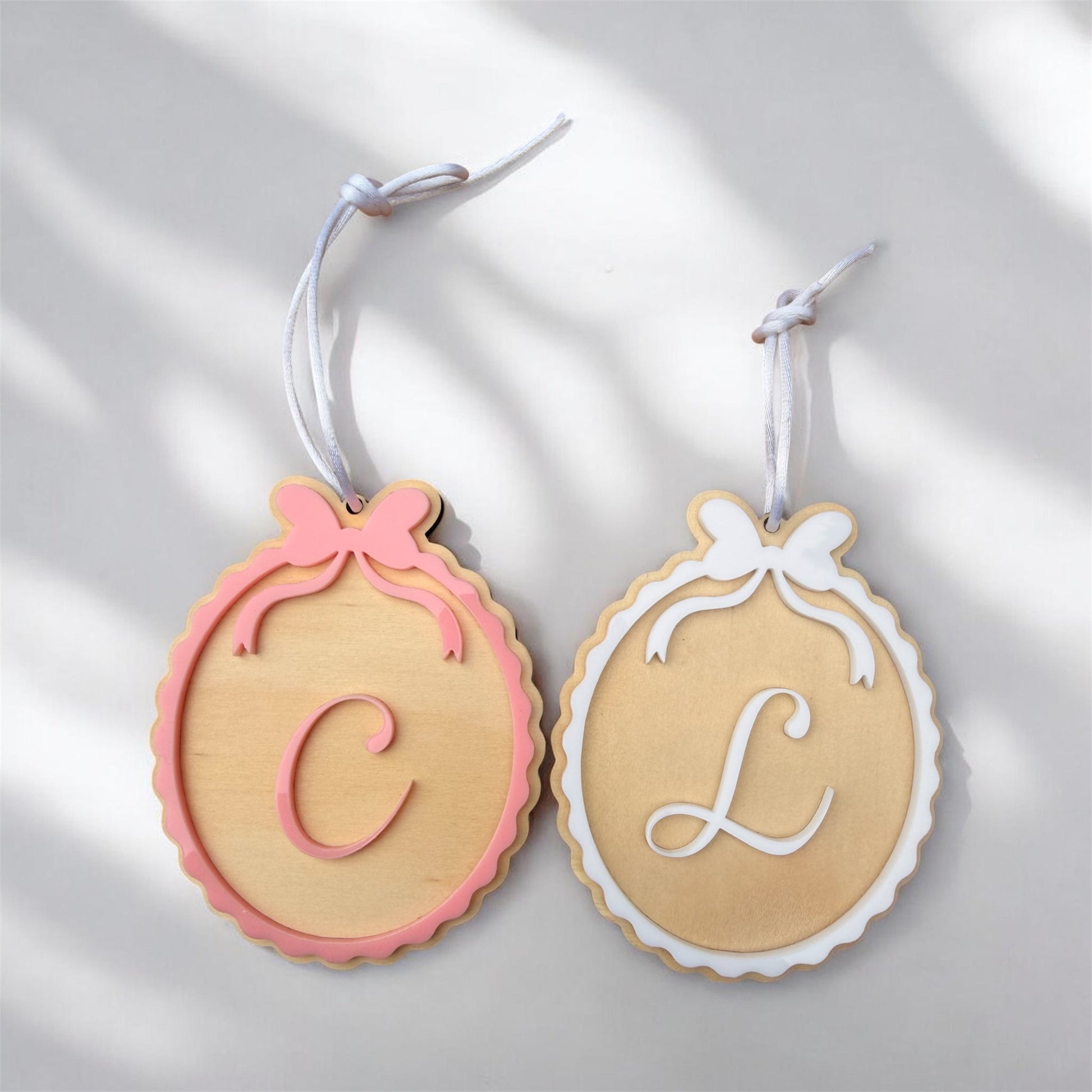 Decorative ornaments with C and L with white and pink bows in scalloped design