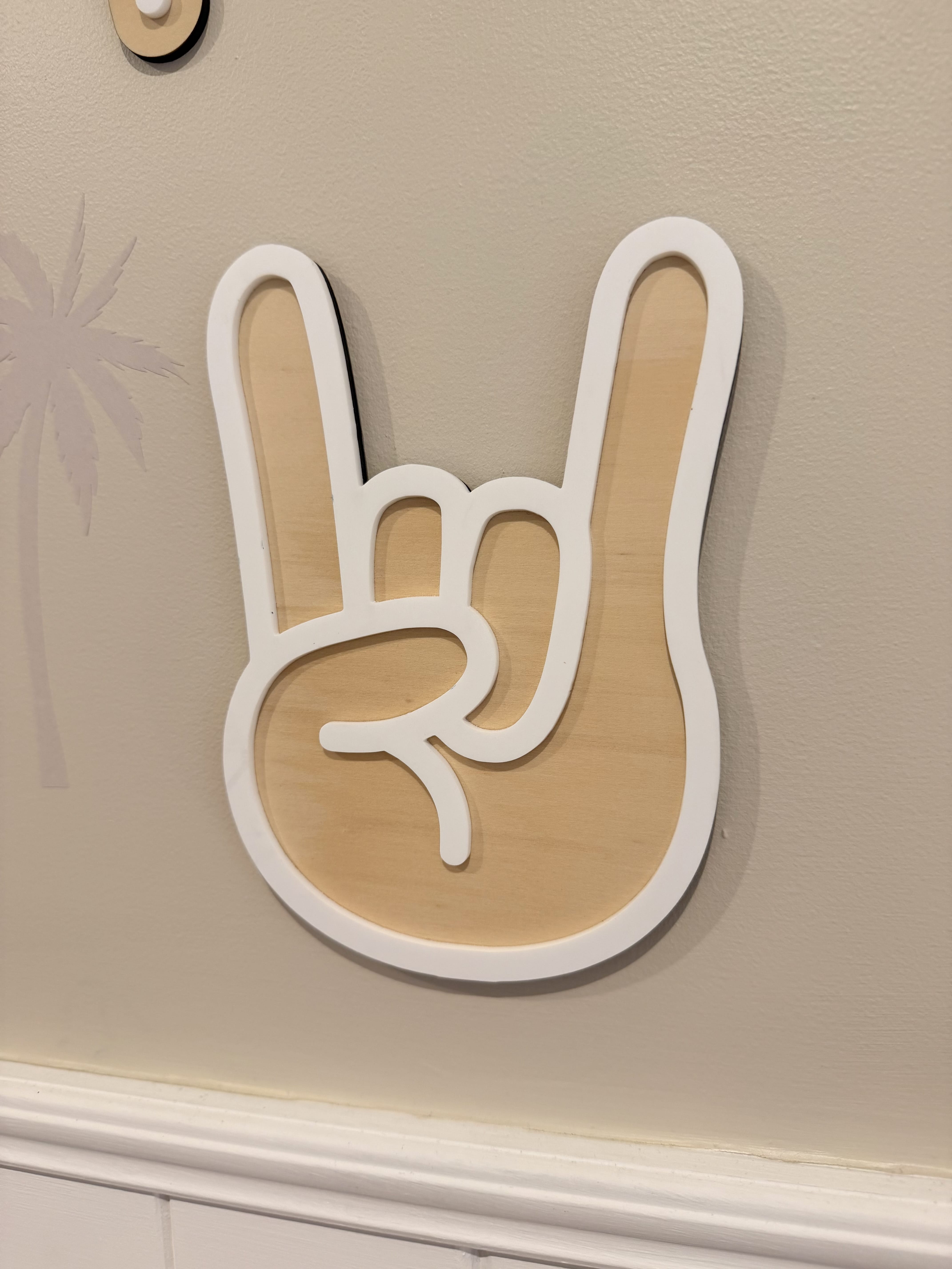 Wooden rock on hand sign hanging on beige wall